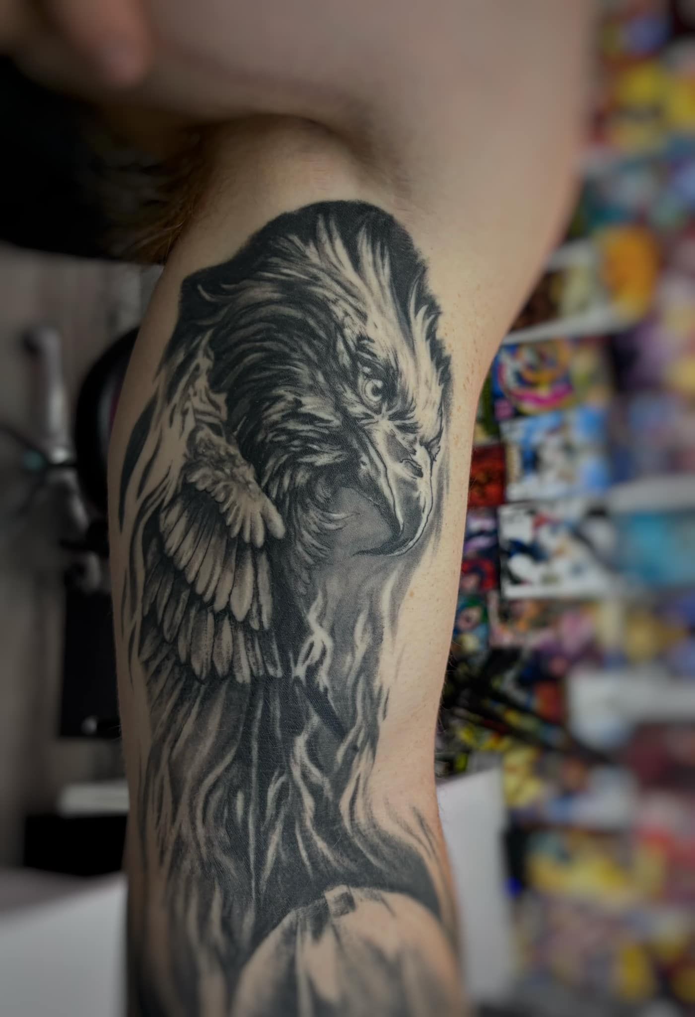 Black-and-gray tattoo of a lion and wings on a person’s upper arm