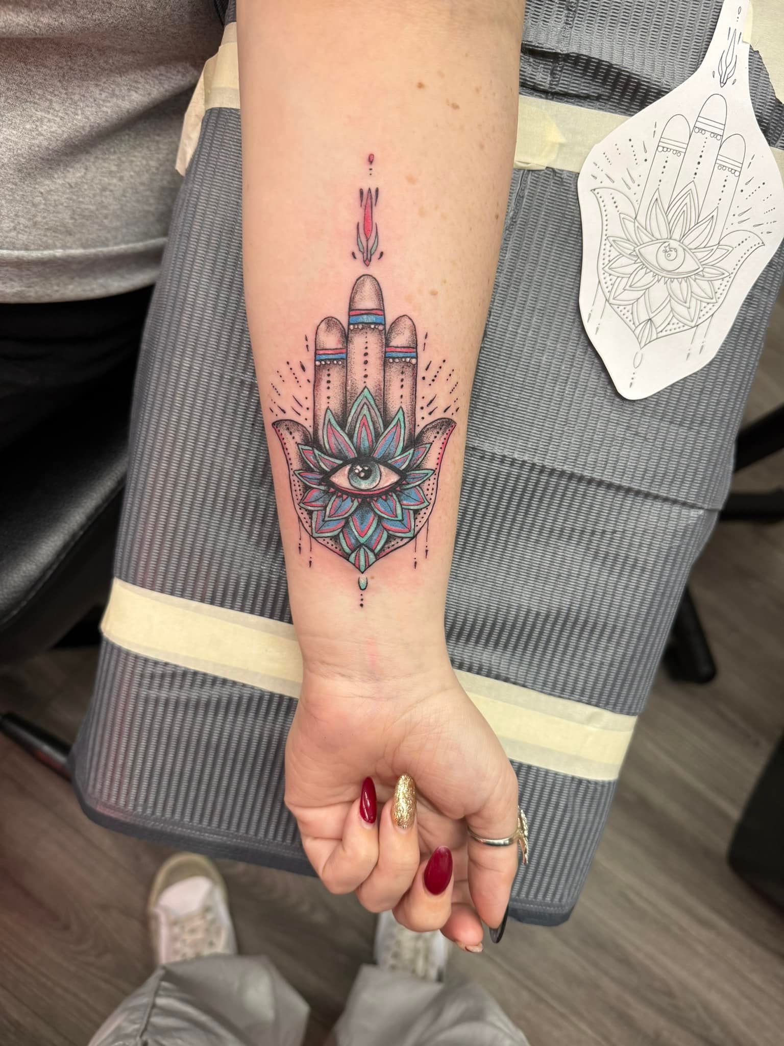Forearm tattoo of a moon and floral mandala on a raised arm, with a gray bandage visible nearby