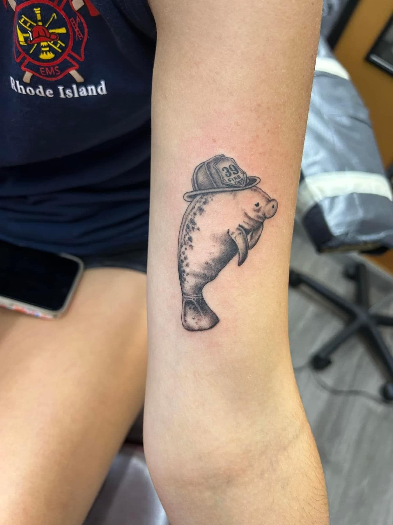 Forearm tattoo of a fish wearing a hat, shown on a person's arm