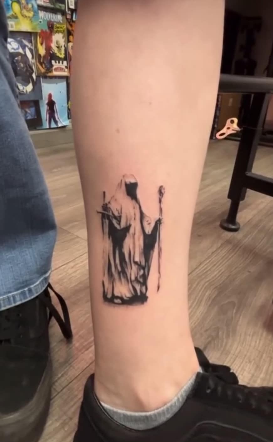 Close-up of a lower leg with a small black abstract tattoo above a shoe.