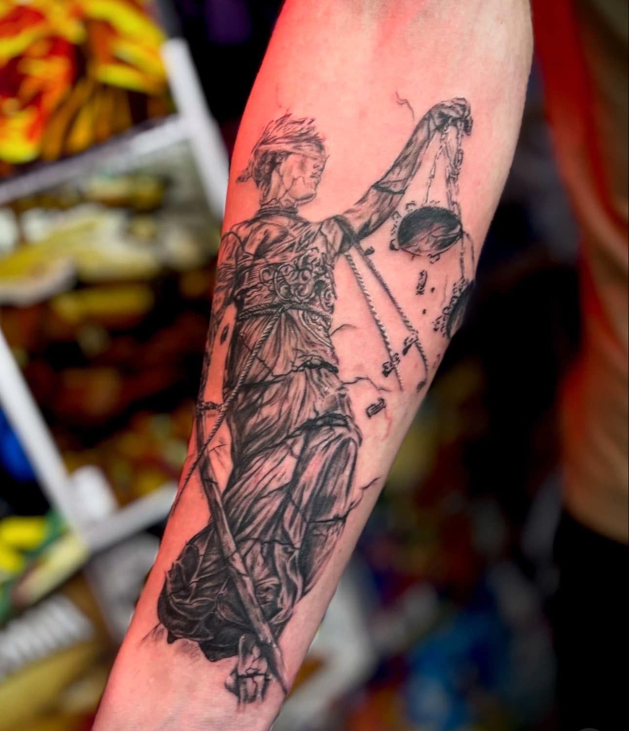 Close-up of an arm with a black linework tattoo of a winged figure holding a bow.