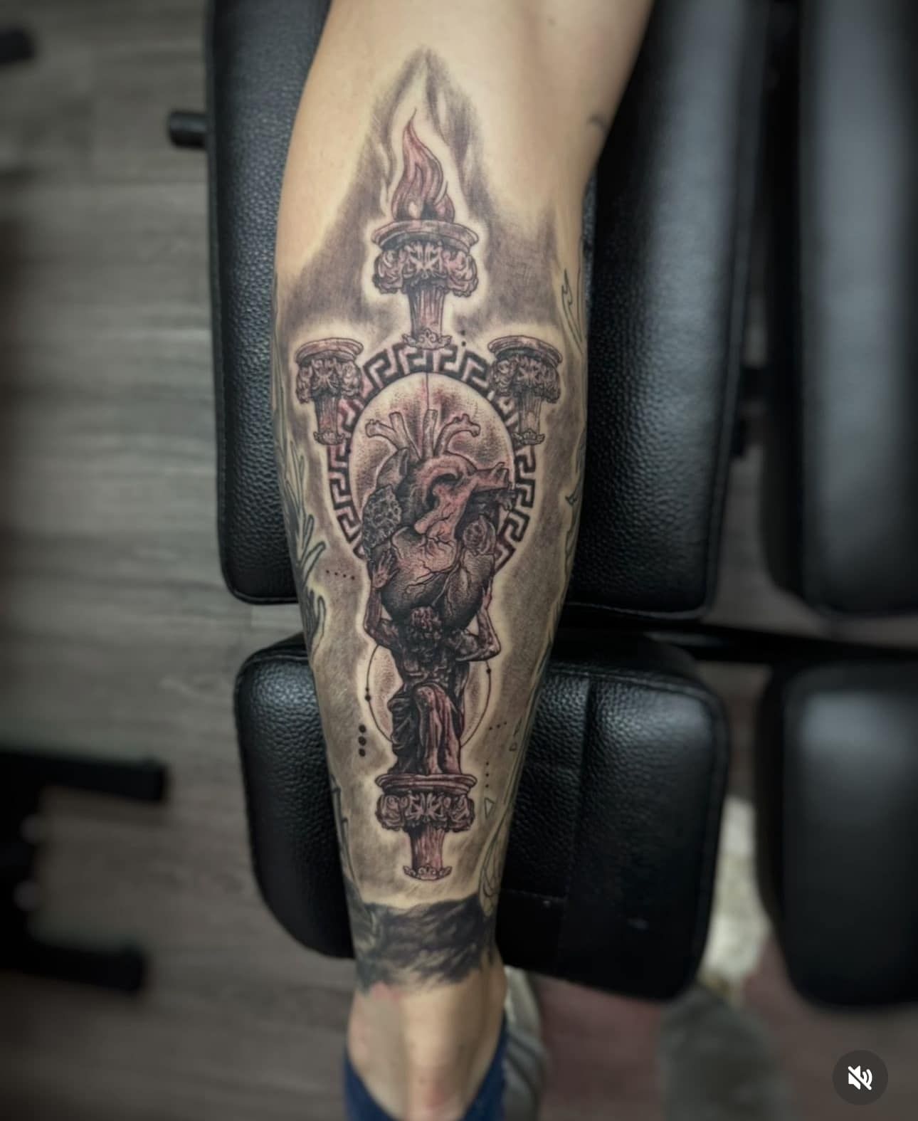 Lower leg with a large dark tattoo featuring ornate circular and spade-like designs