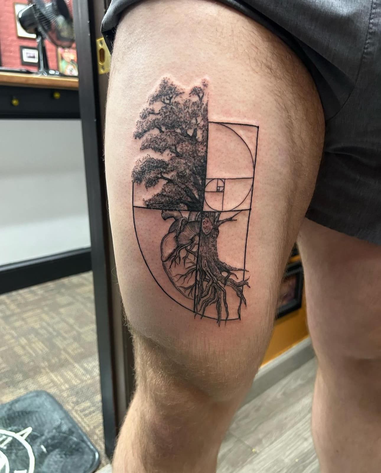 Close-up of a leg tattoo with a tree silhouette and geometric linework on the calf.