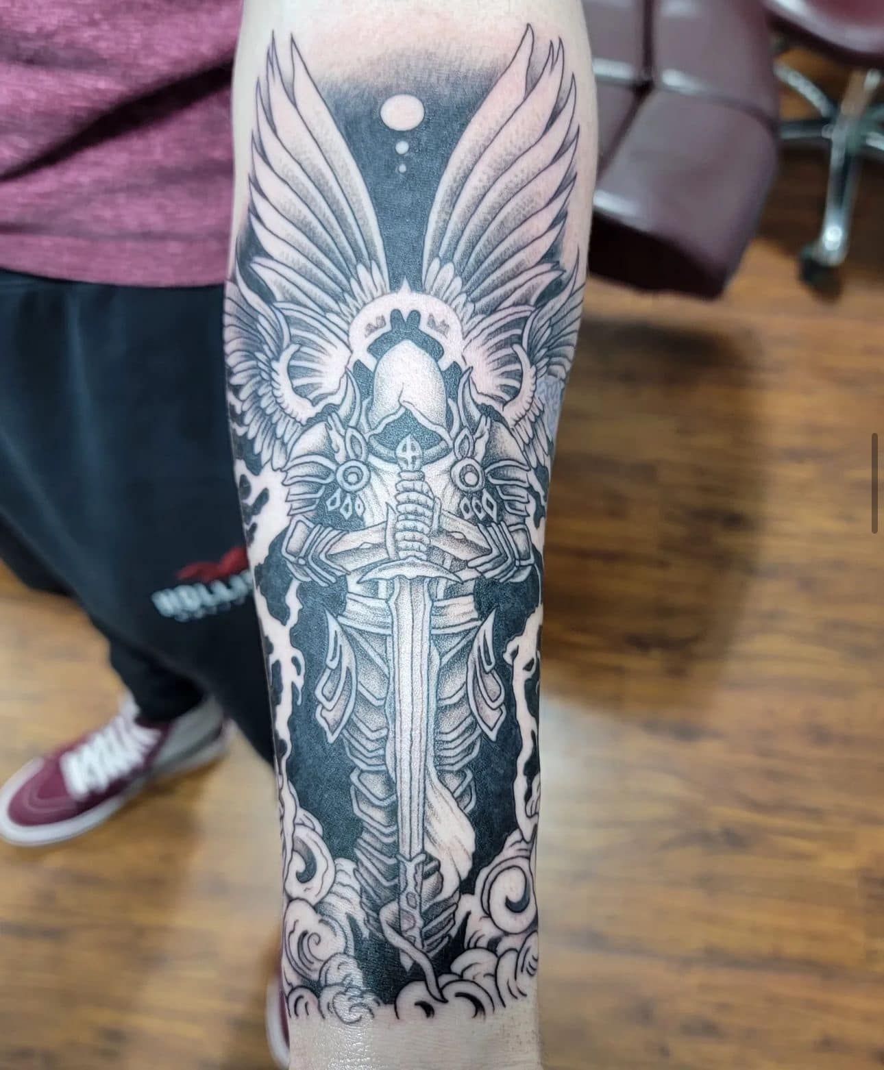 Leg tattoo of an angel with wings and ornate details in black and gray