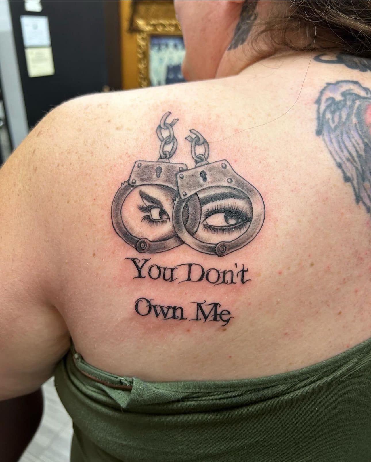 Back tattoo reading “You Don’t Own Me” with a brass knuckles design above it