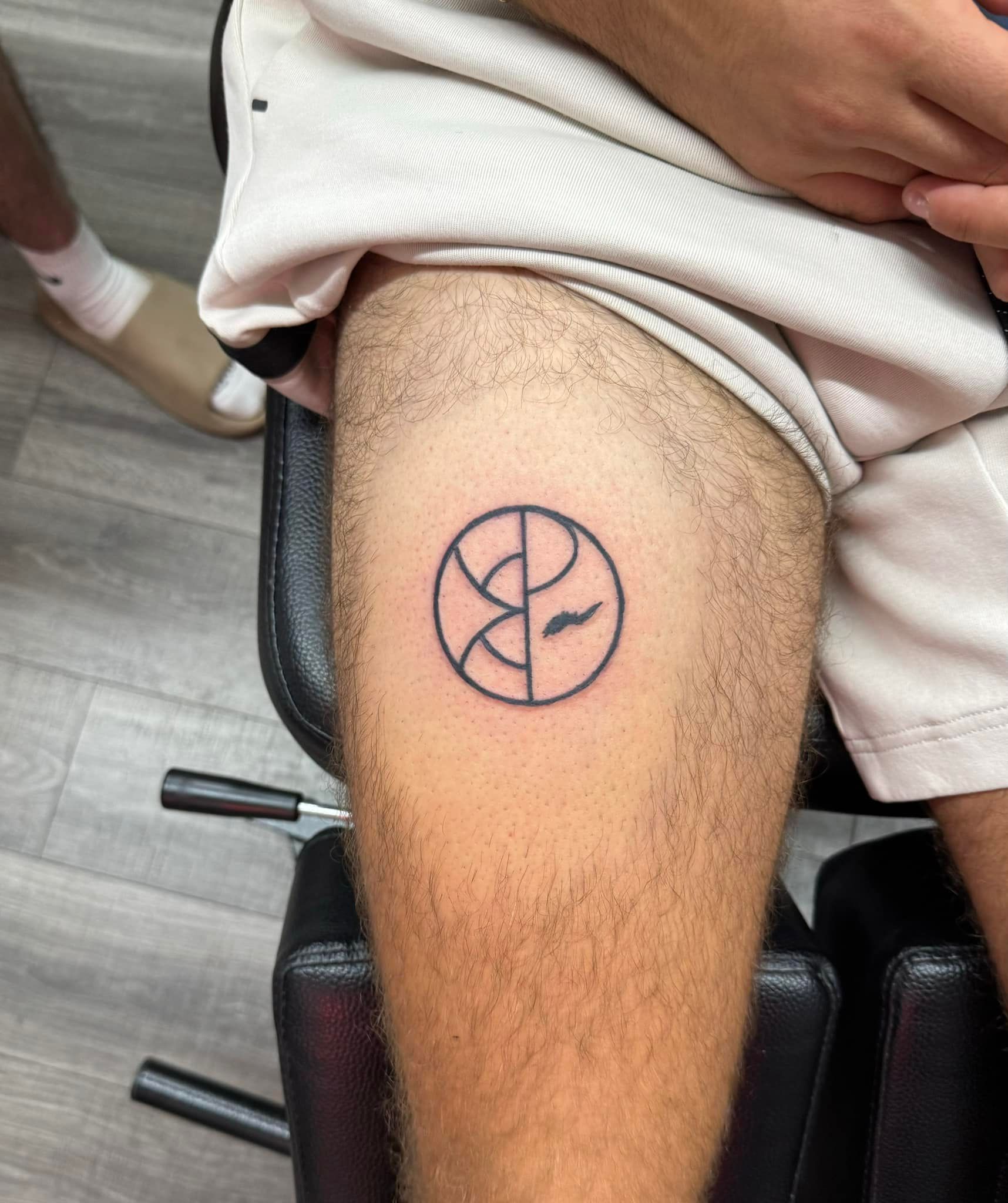 Tattoo of a circular abstract design on a person’s upper thigh at a tattoo studio