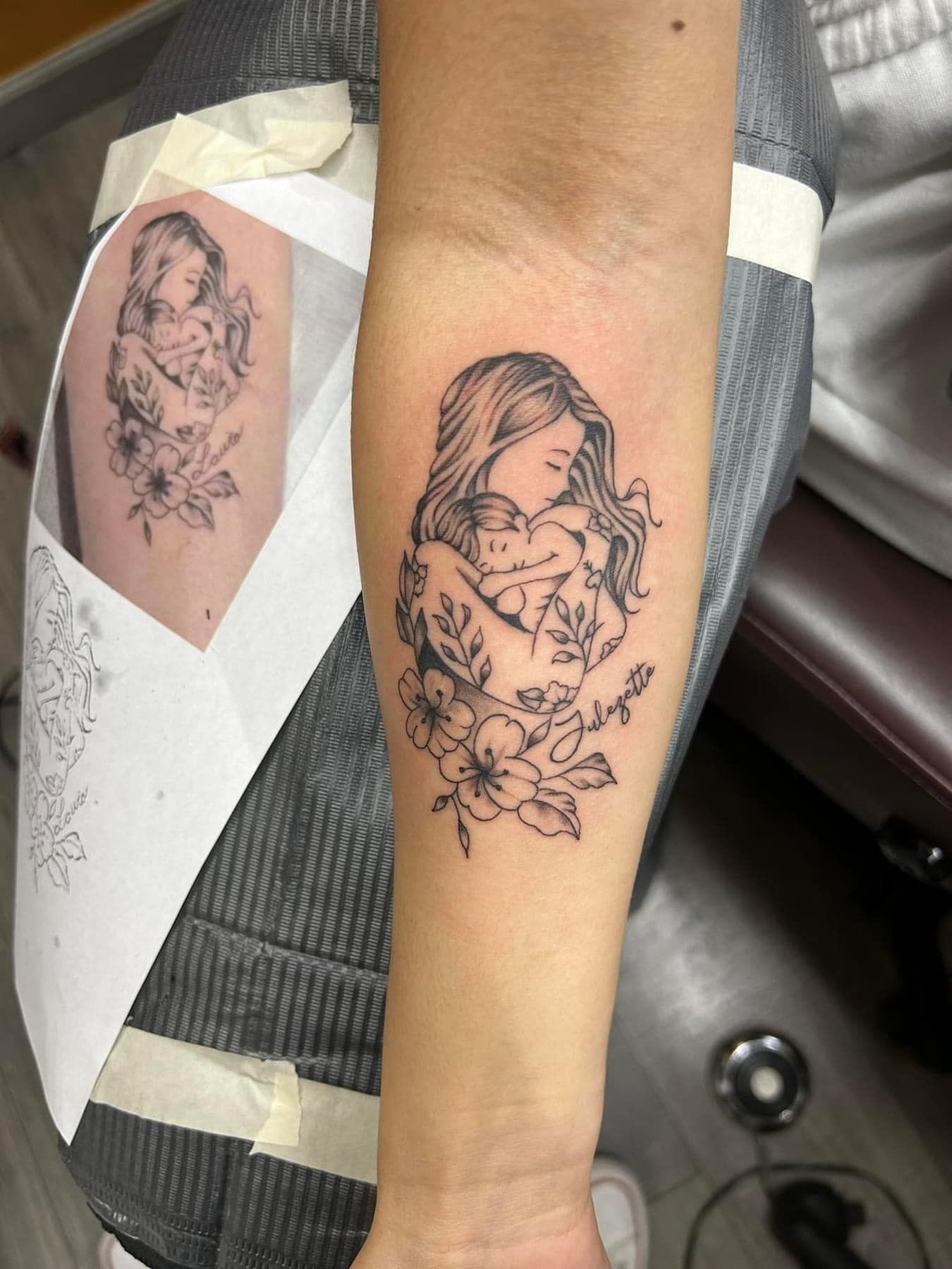 Forearm with a black line-art tattoo of a woman holding flowers, next to the stencil reference on paper.