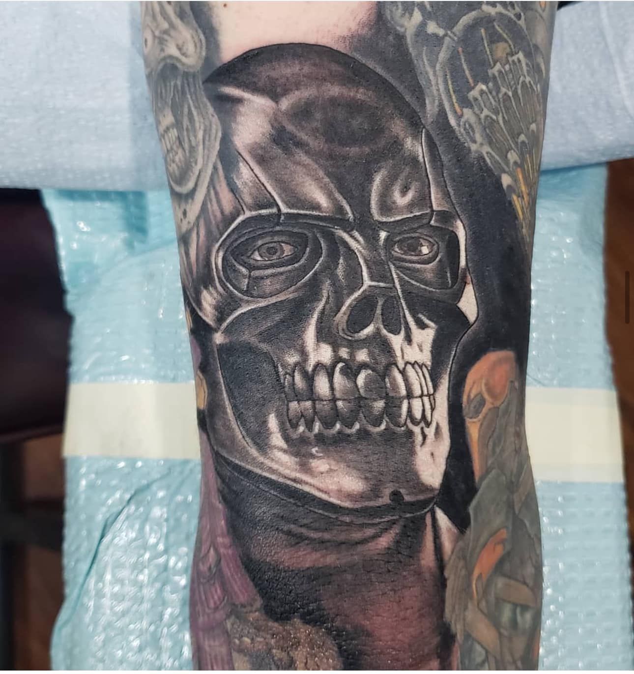 Close-up of a black-and-gray skull tattoo on a forearm with ornate shading