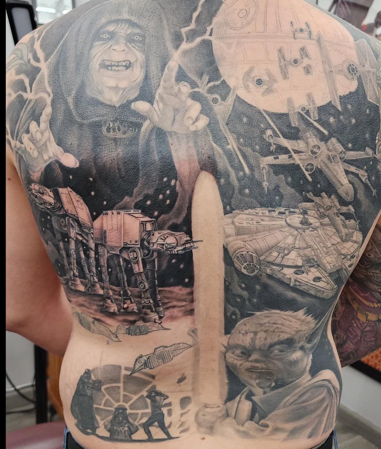 Back tattoo with a hooded figure, a moonlit scene, and a child’s face in grayscale ink