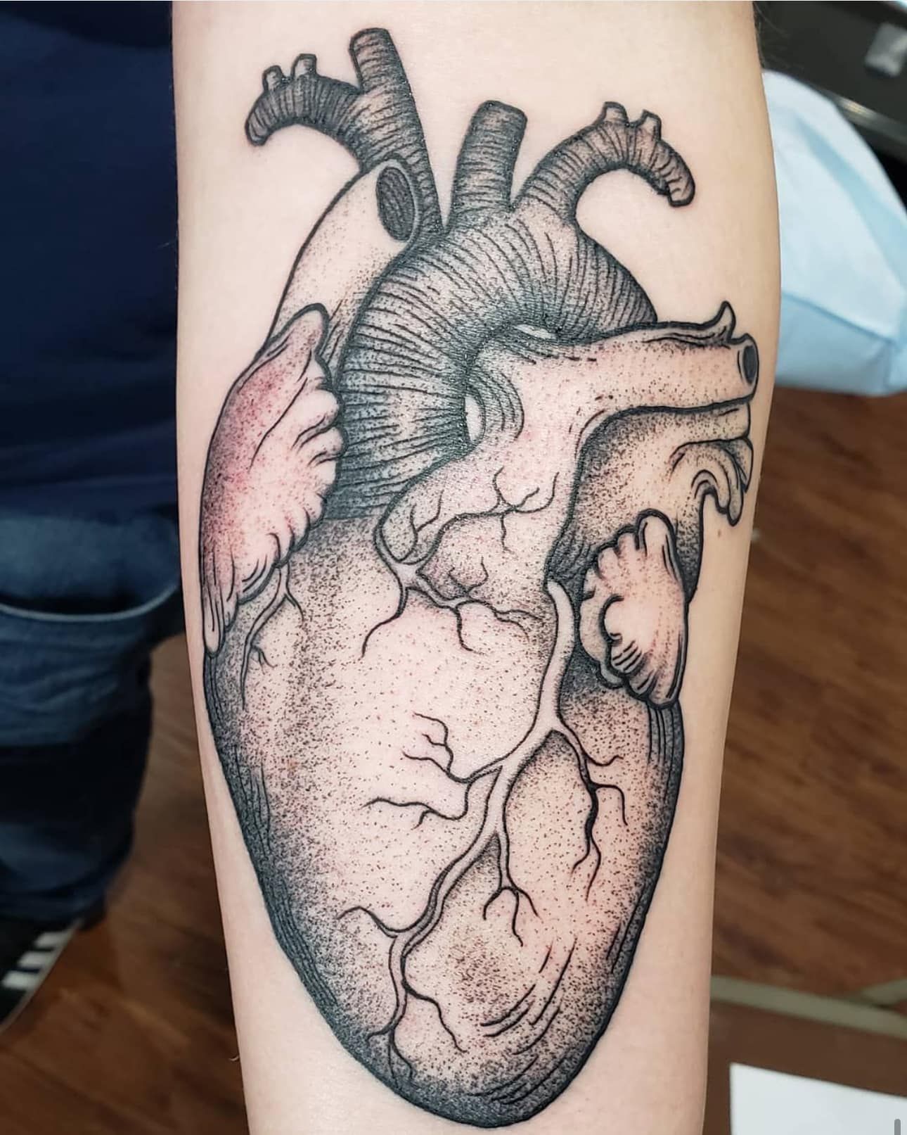 Black-and-gray tattoo of an anatomical human heart on a person’s forearm