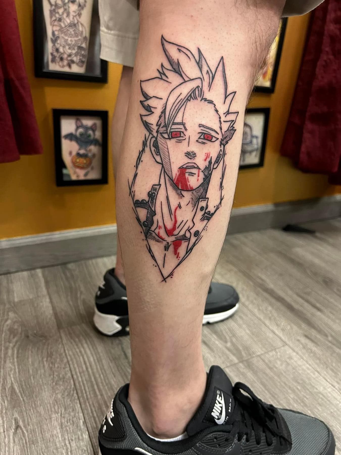 Tattoo design of an anime-style face on a lower leg in a tattoo shop