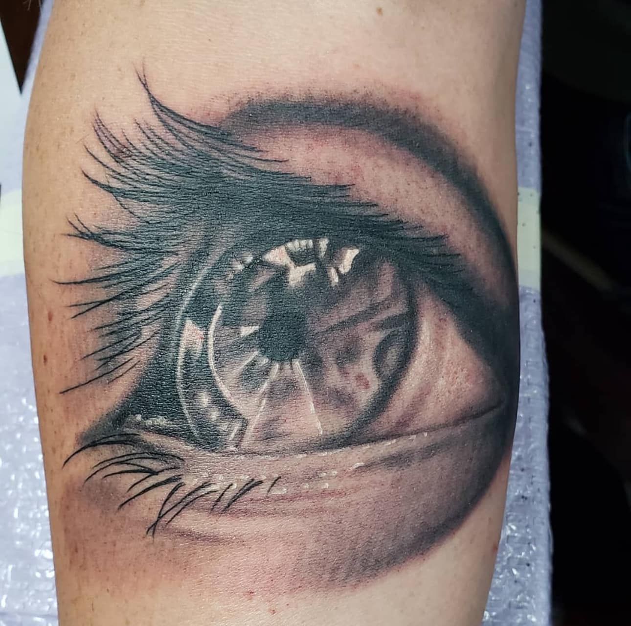 Close-up of a realistic black-and-gray eye tattoo on skin