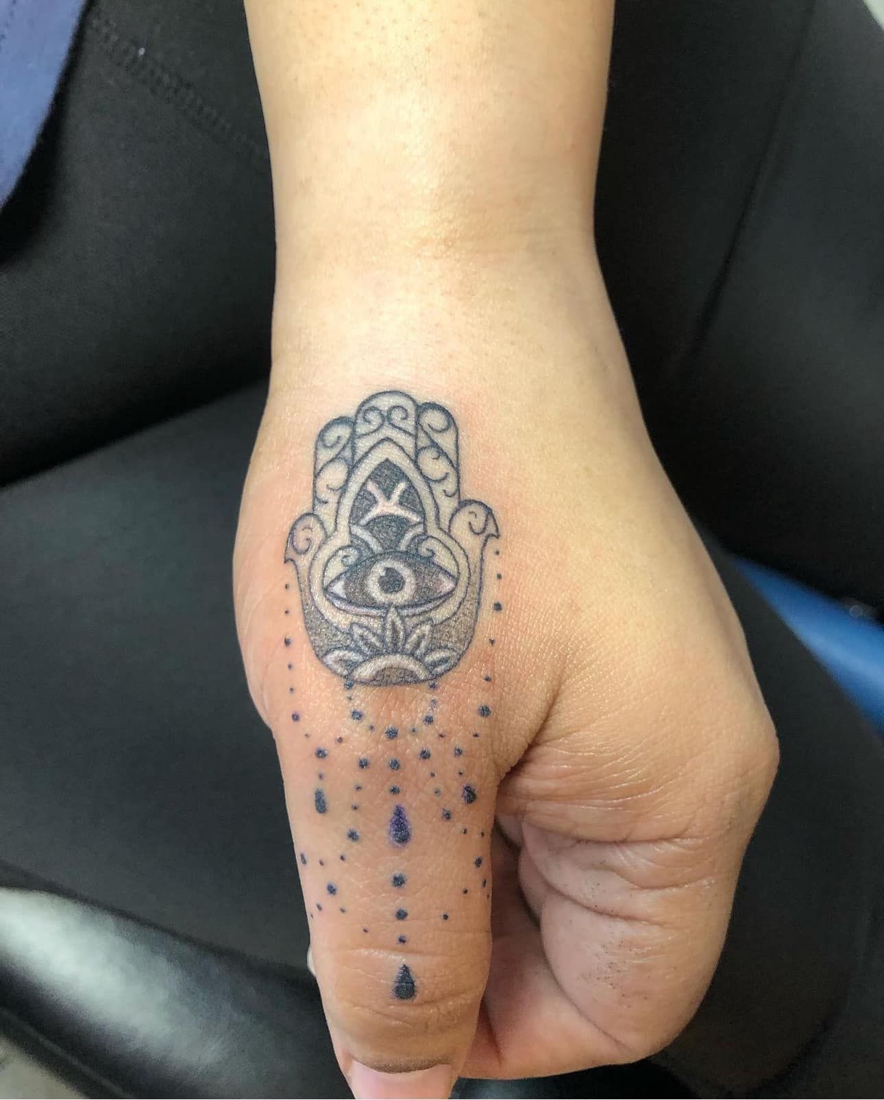 Hand with ornate black henna tattoo on the back, dotted pattern extending toward the wrist