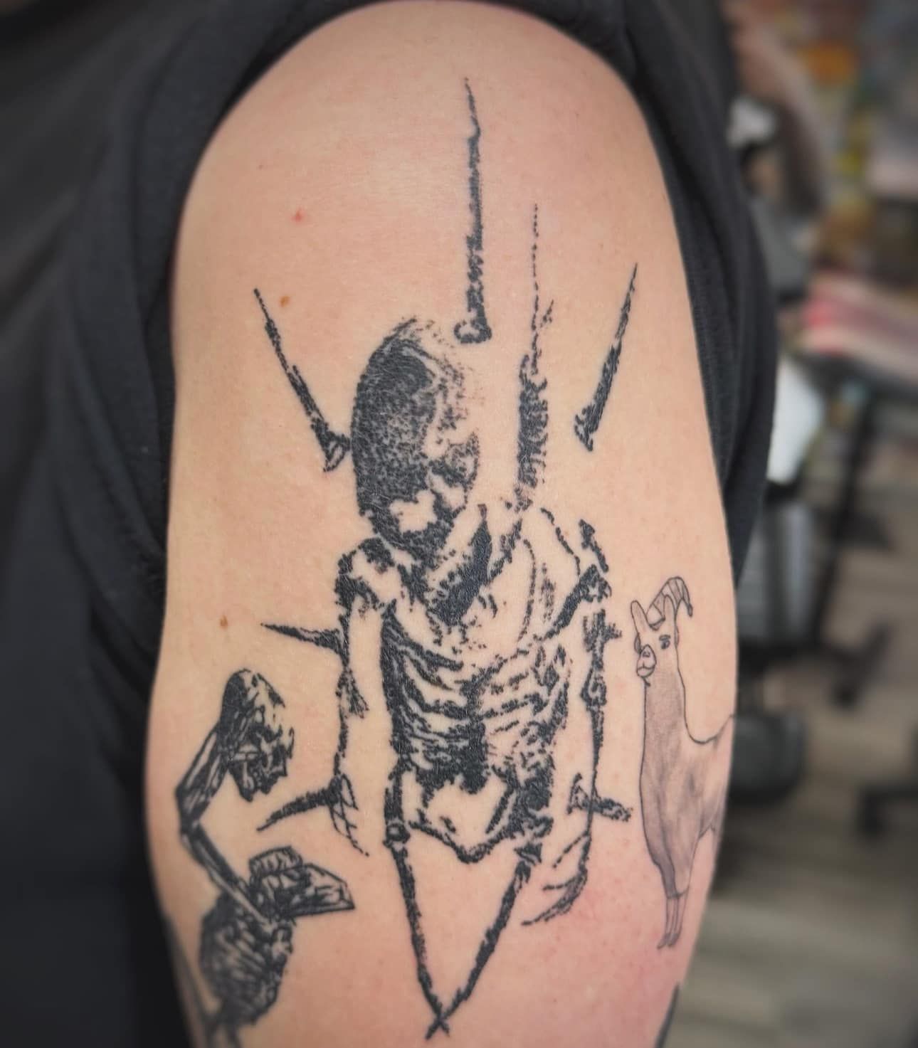 Black insect tattoo design on a person’s upper arm, with sketchy dark lines on skin