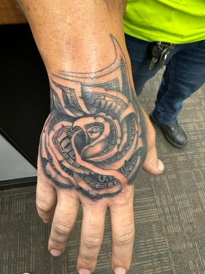 Close-up of a hand and wrist with a black rose tattoo, palm facing up.