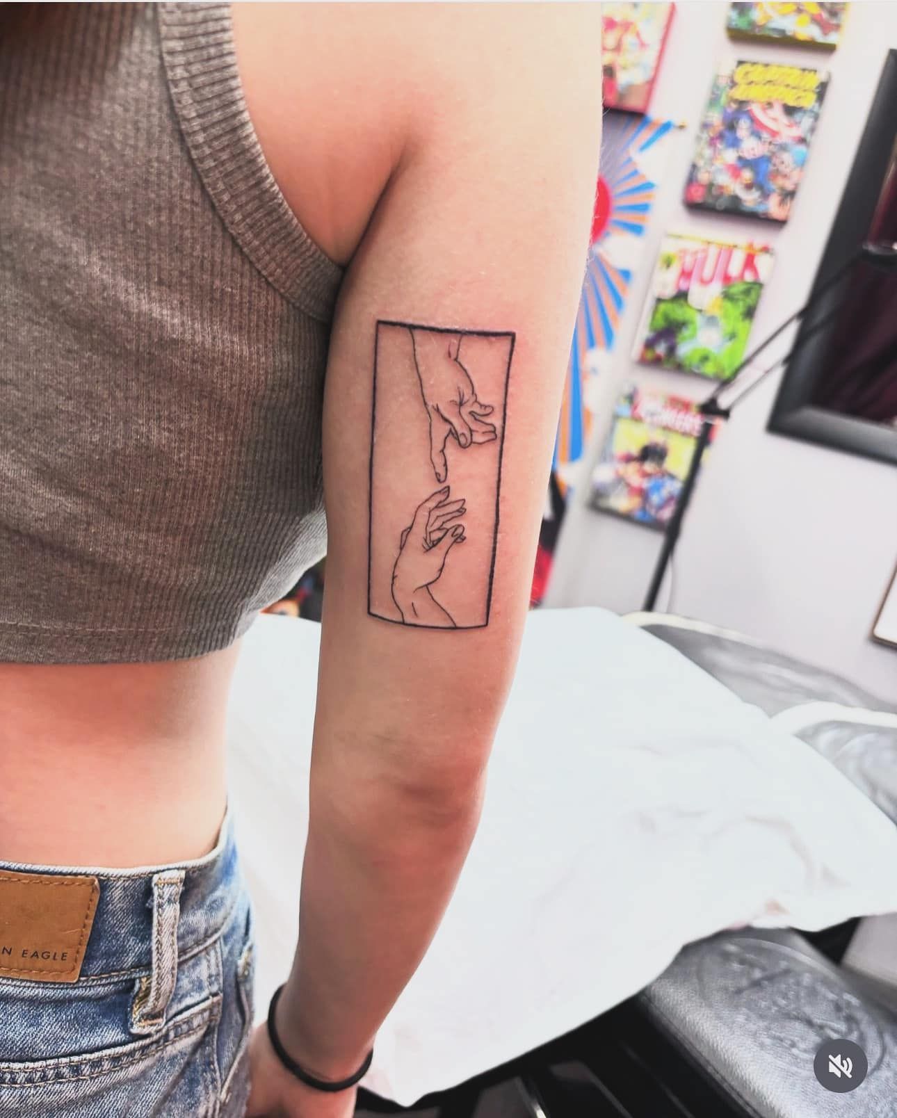 Arm with a rectangular tattoo of a geometric map-like line design in a room with shelves in the background