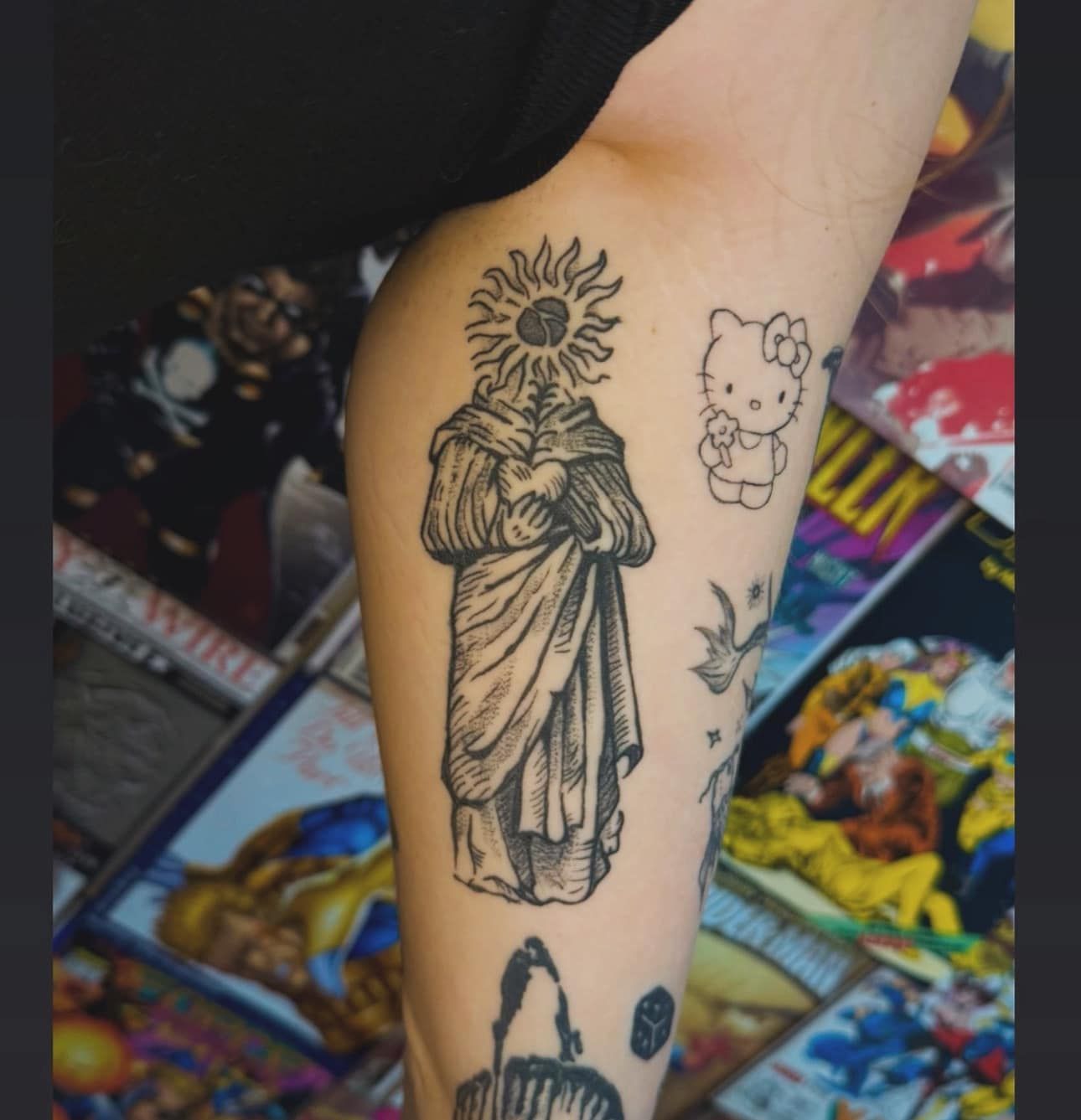 Forearm tattoos, including a saint with a sunflower halo and small cartoon-style designs.