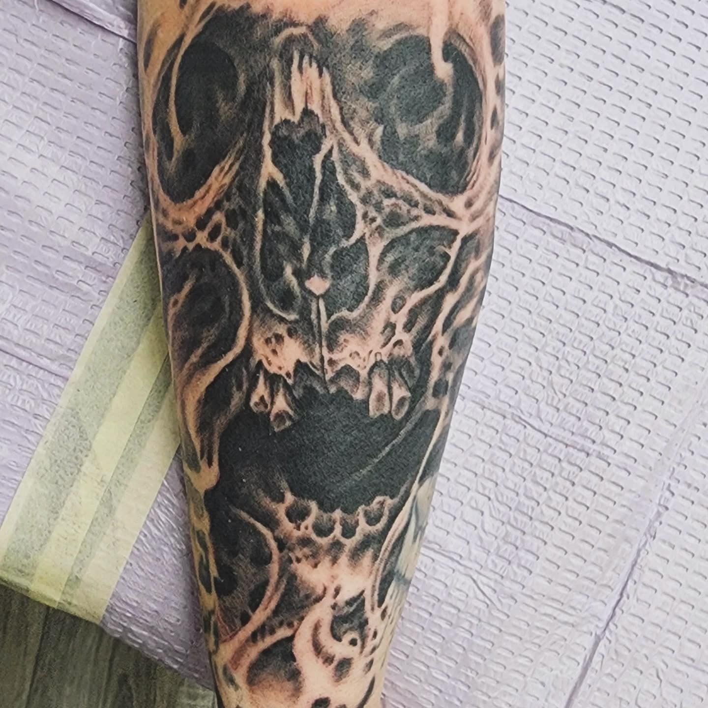 Close-up of a forearm with a black-and-orange skull tattoo resting on a striped cloth.