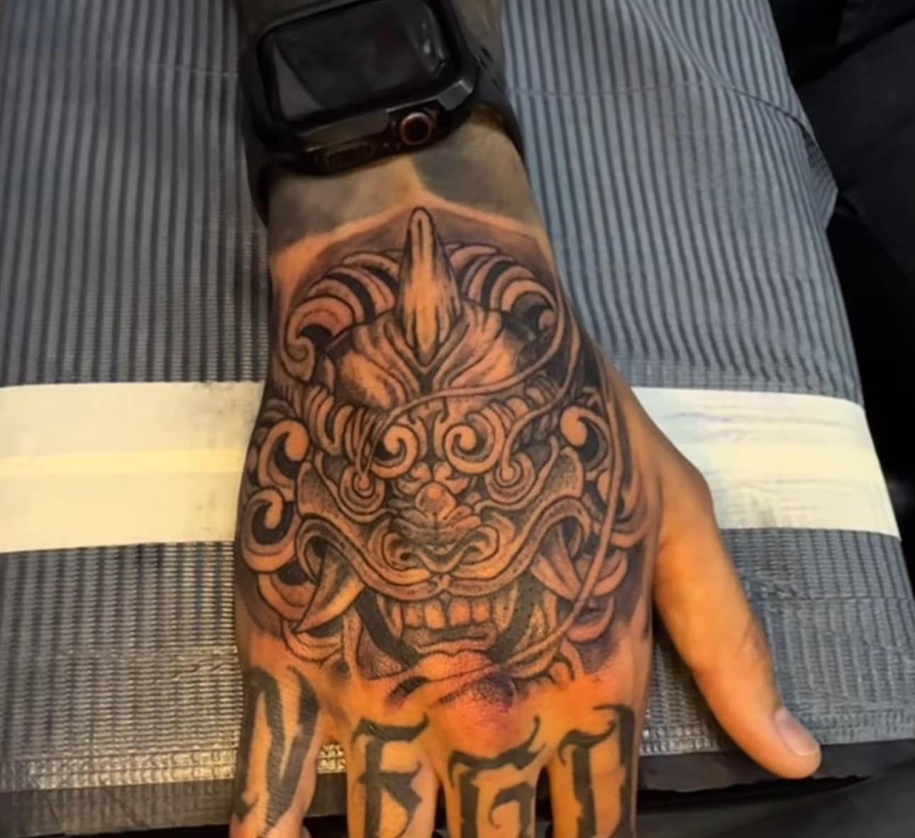Hand tattoo with an ornate black-and-red tiger face design on a wrist and hand