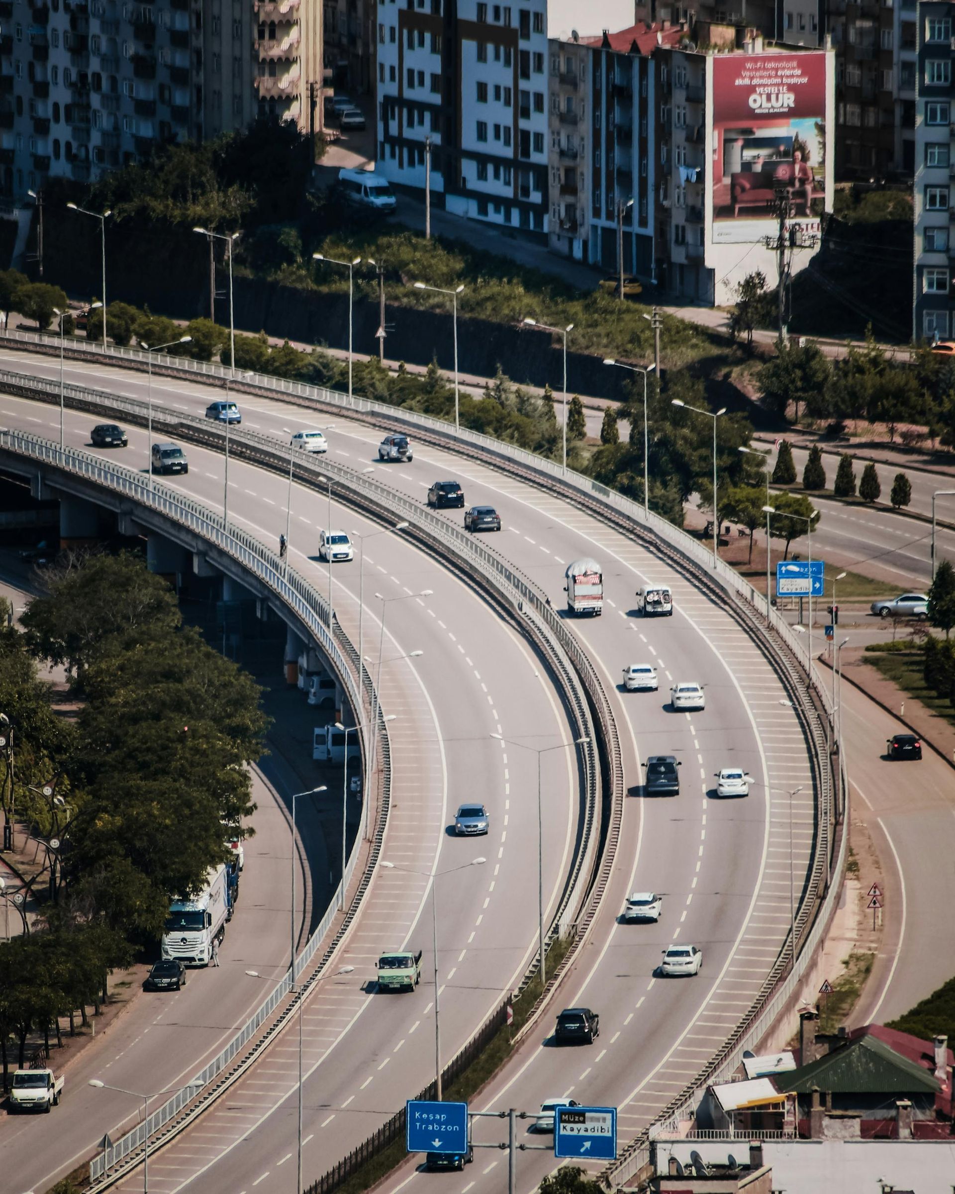 Curving elevated highway with light traffic beside city buildings and trees