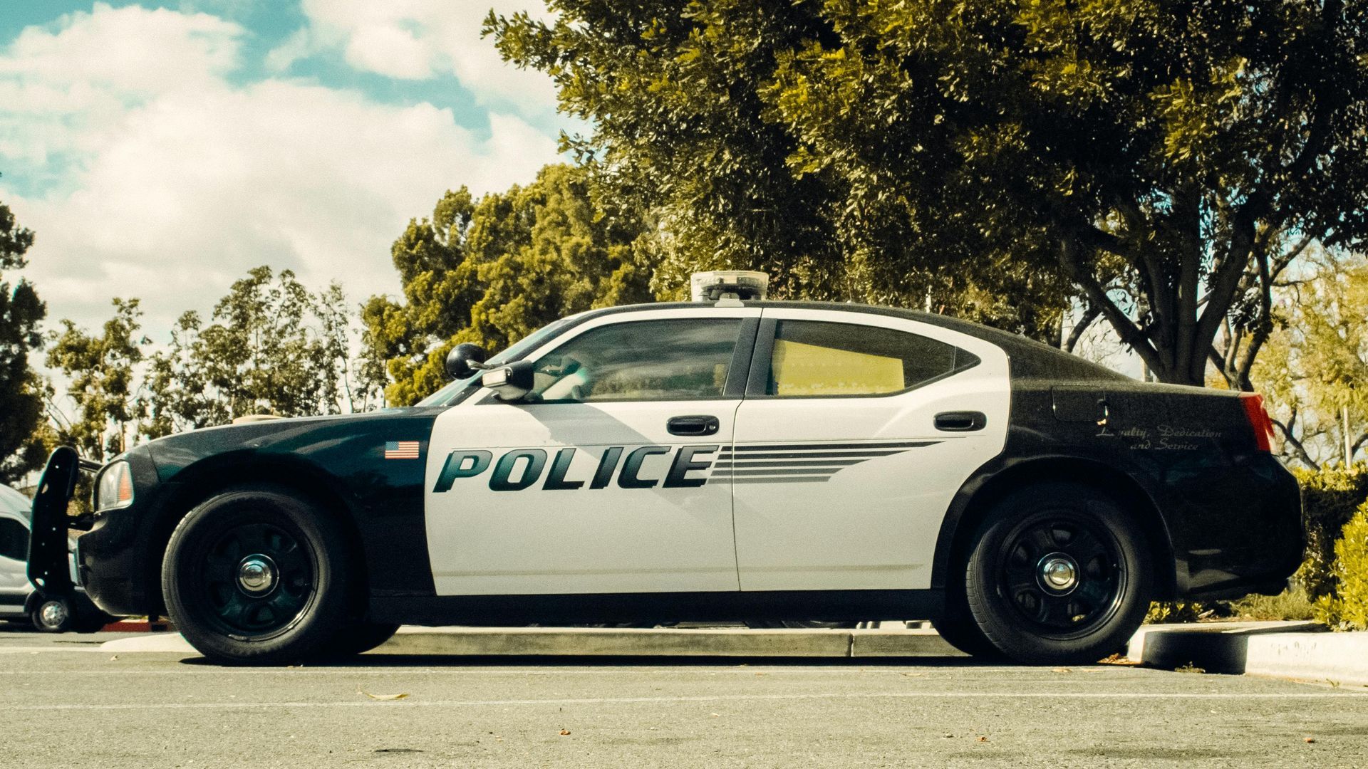 A black and white police cruiser parked in an outdoor lot on a sunny day.
