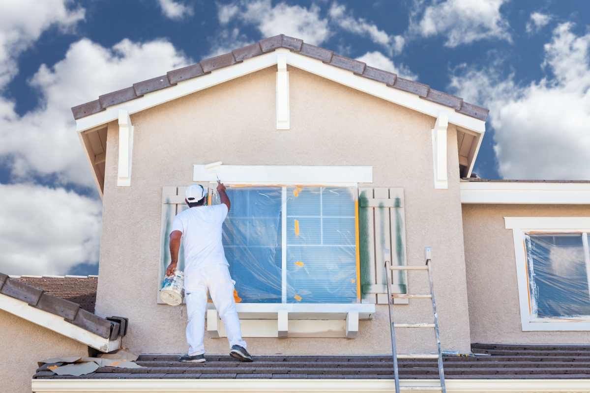 Two people using Regal Select Exterior Paint on the front of a home