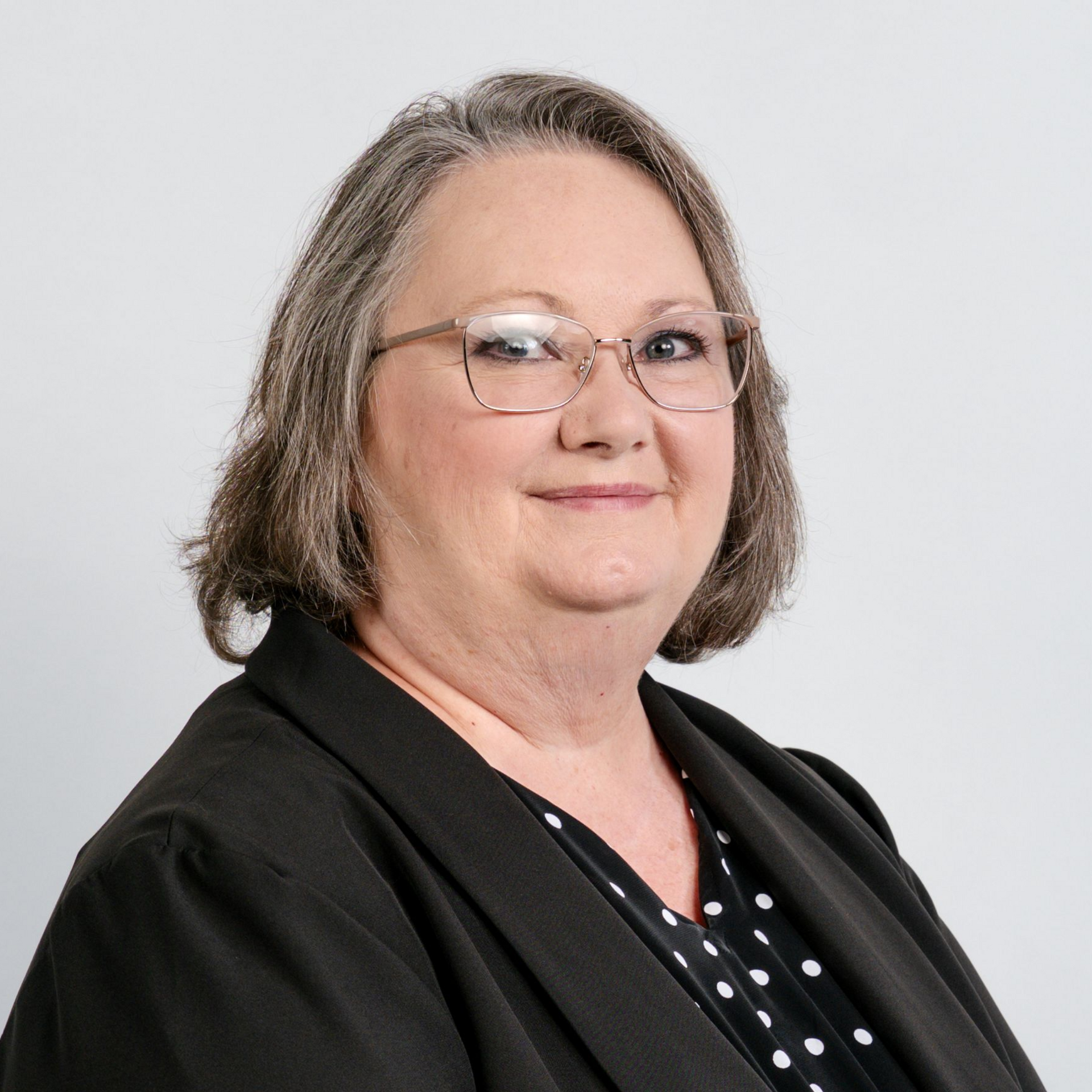 A woman wearing hoop earrings and a white shirt is smiling for the camera.
