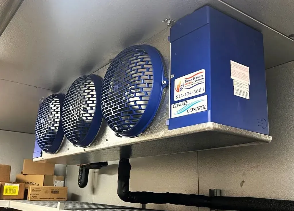 Blue ventilation fans and ducting mounted on a ceiling shelf in a utility room
