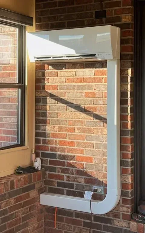 White rectangular wall-mounted frame with a curved lower section on a brick wall next to a window