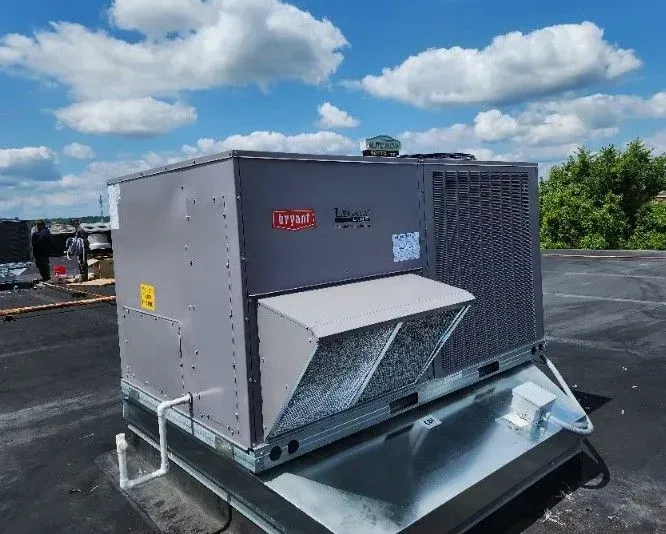 Gray rooftop HVAC unit with a front vent on a flat roof under a partly cloudy sky