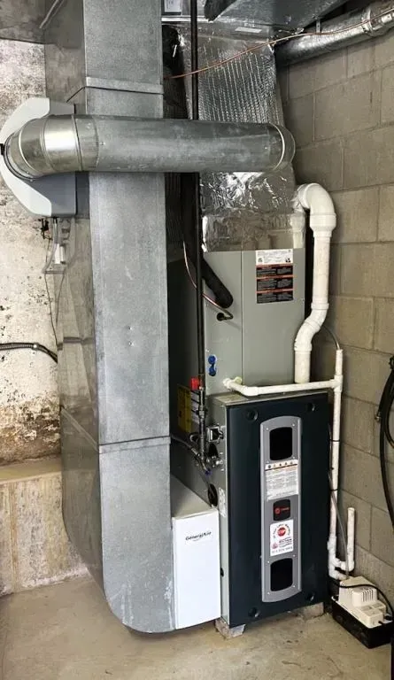 Basement furnace and water heater with metal ductwork and white PVC vent pipes