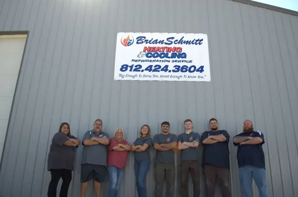 Seven people standing in front of a metal building with a Schutte sign