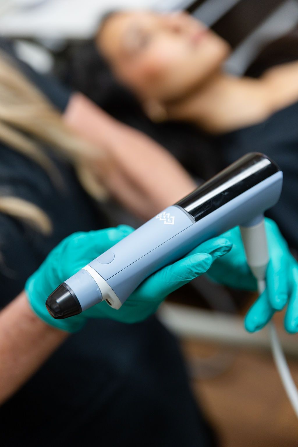 Gloved hands holding a handheld skin treatment device