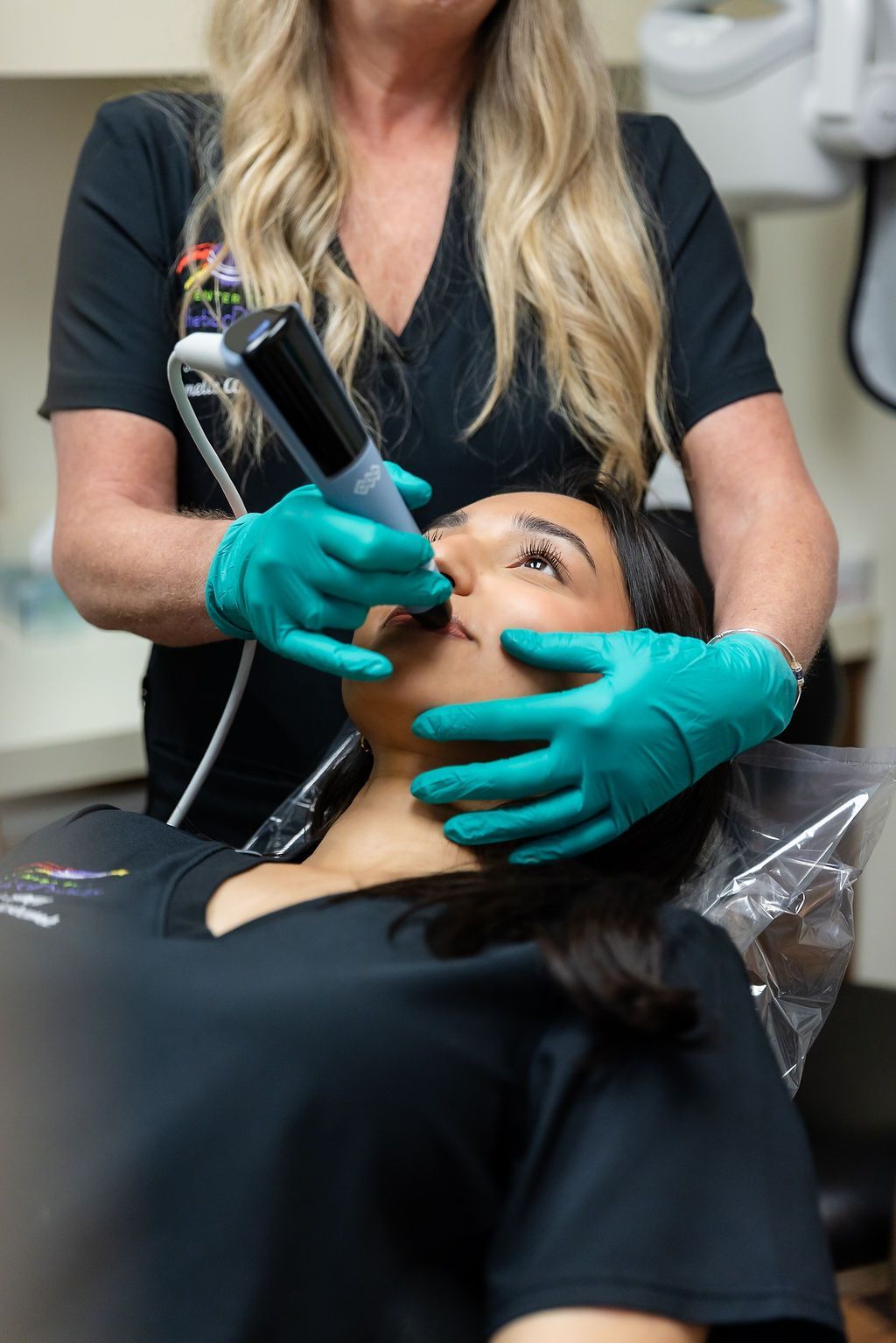 Esthetician using a handheld treatment device on a reclining client’s face