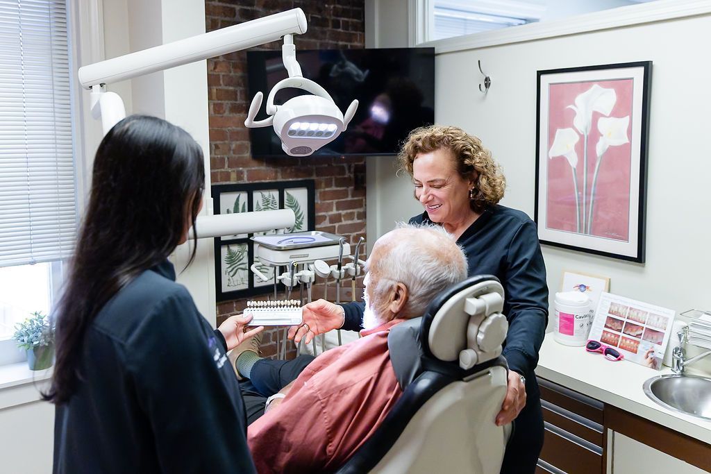 Dental exam with patient in chair and two clinicians in a bright office