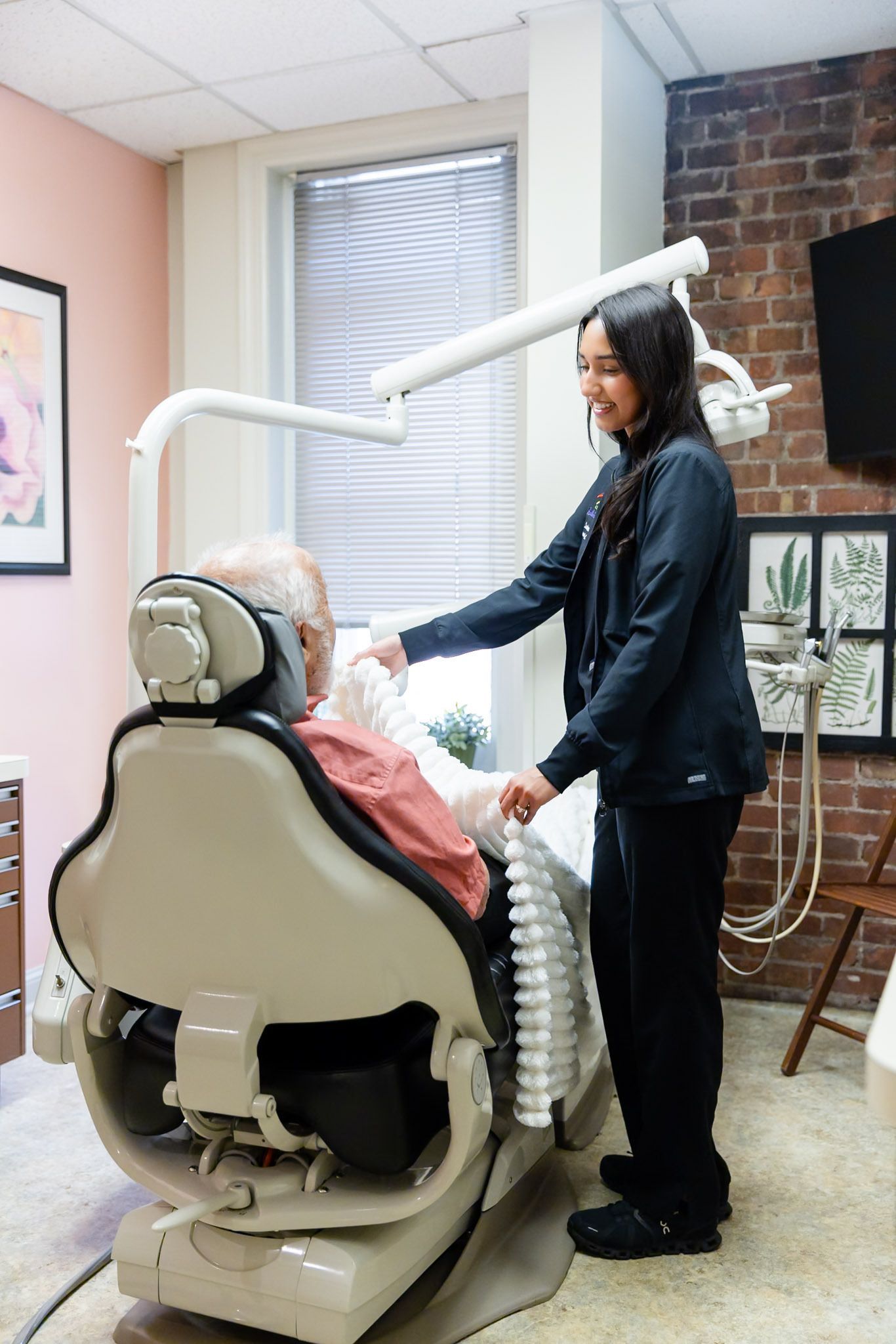Dental hygienist adjusting equipment while a patient sits in a dental chair