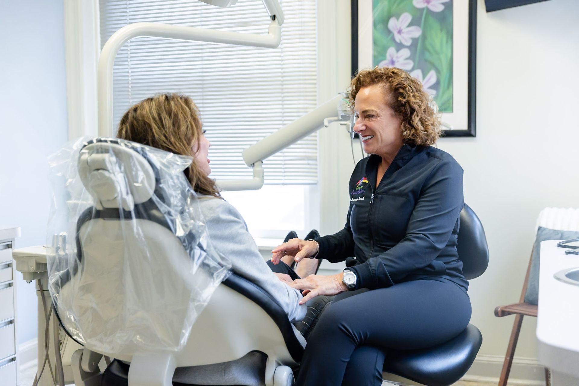 Dentist talking with a patient in a dental chair during an exam