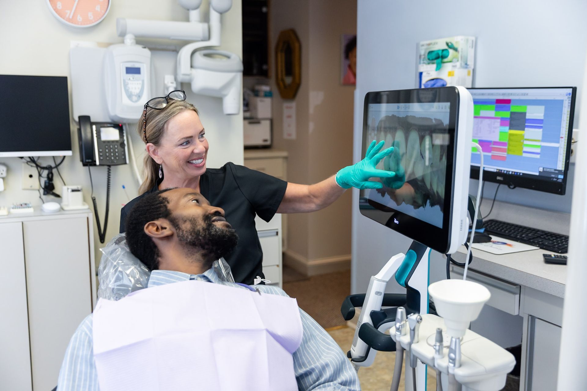 Dentist showing X-ray on monitor while patient reclines in exam chair