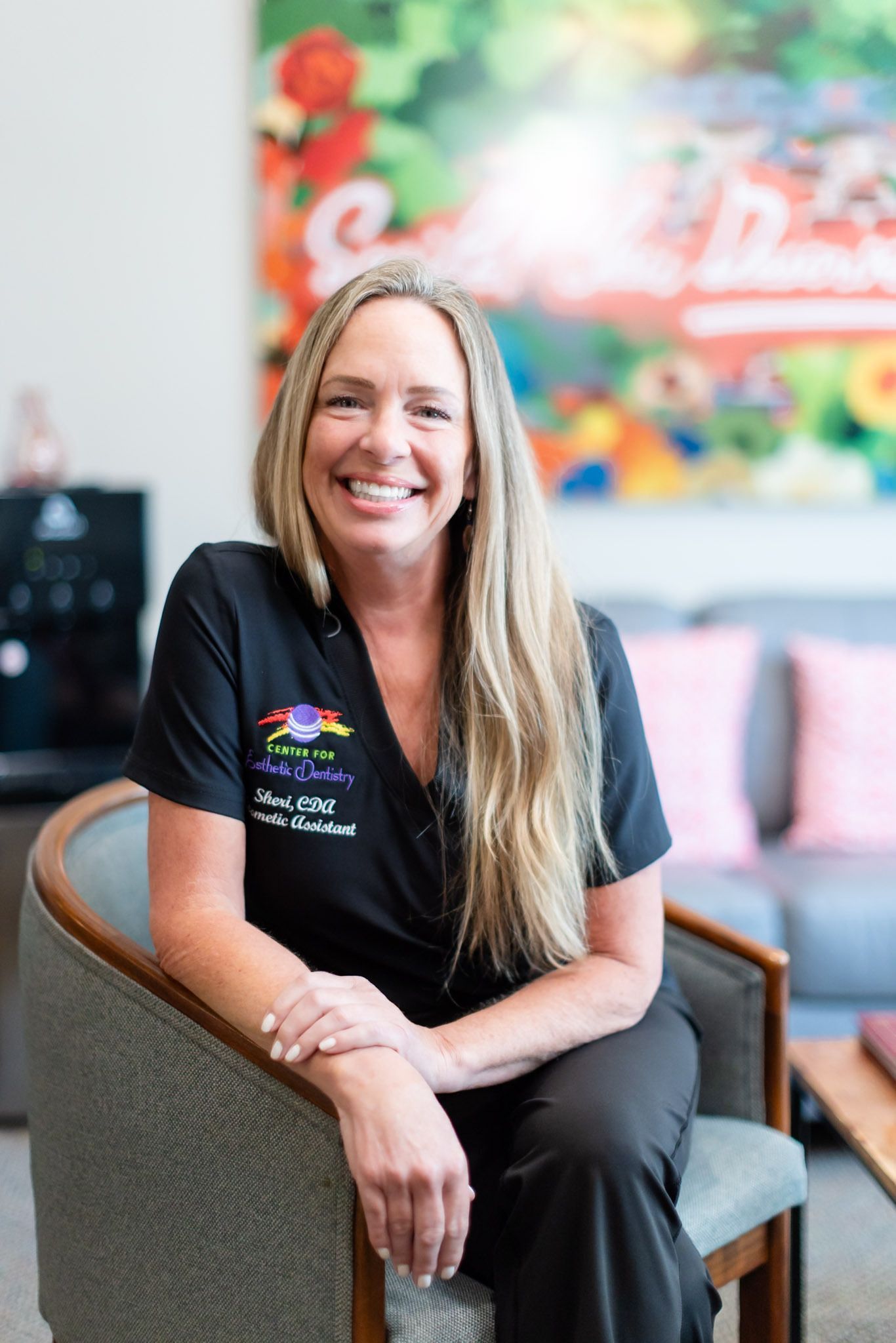 Smiling woman in a black shirt seated in a chair indoors
