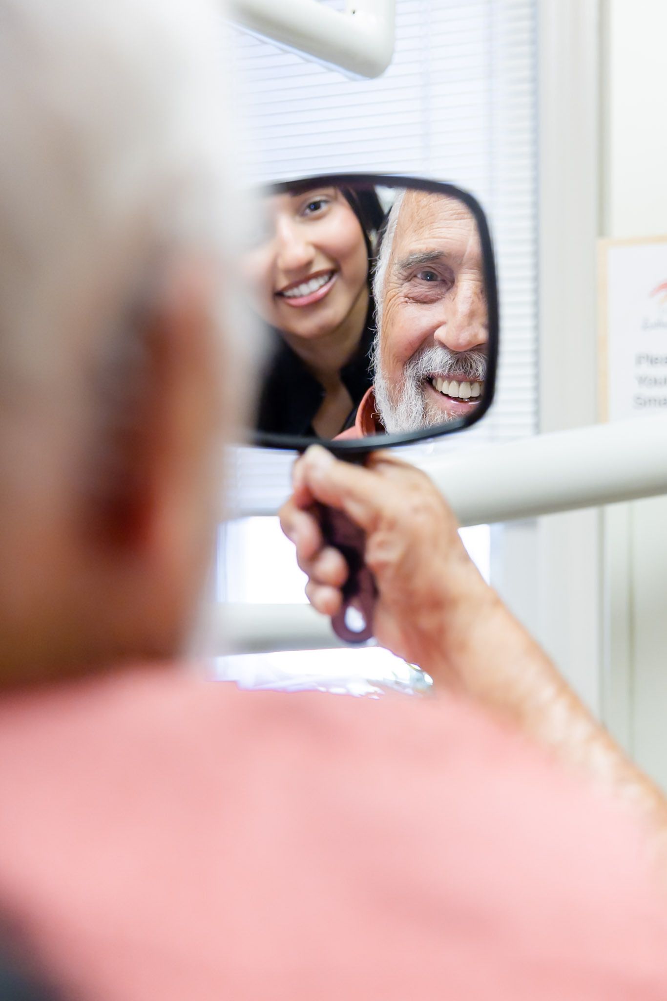 Person looks into a handheld mirror showing a smiling face
