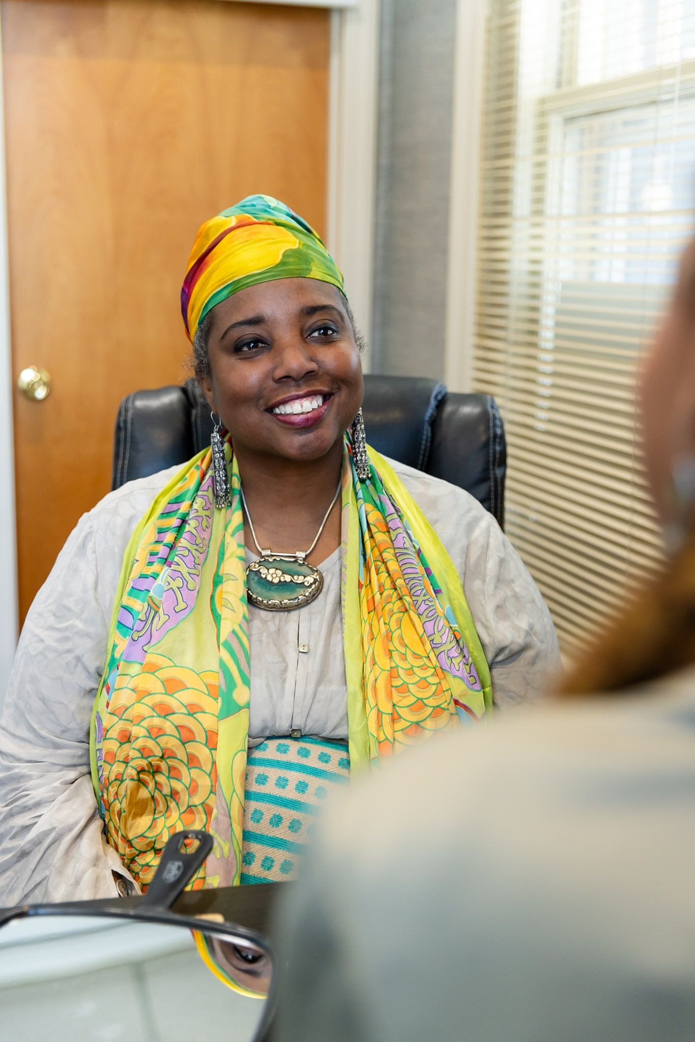 Smiling person in colorful attire seated in an office