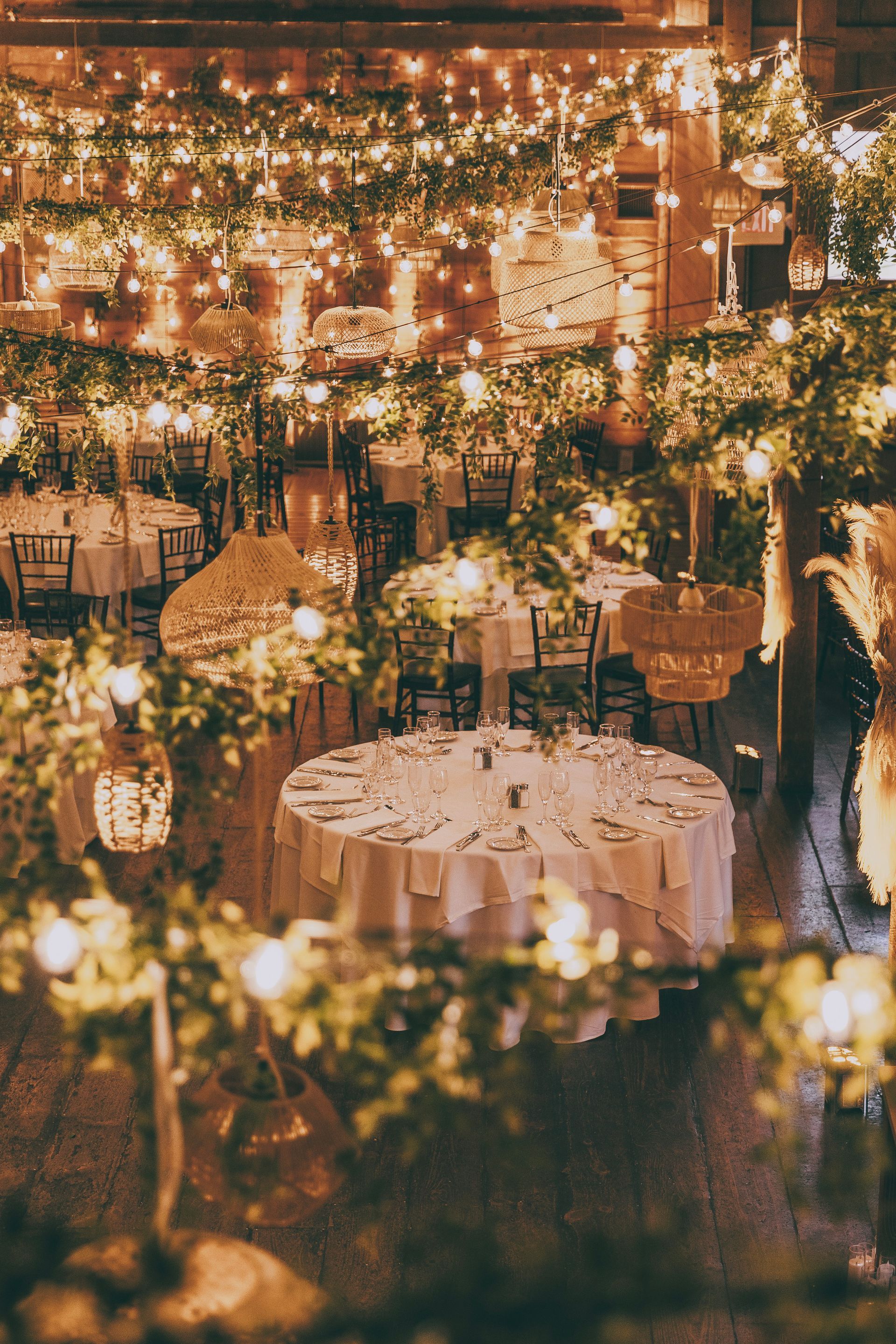 Warm, candlelit indoor wedding reception with flower-decorated tables and string lights