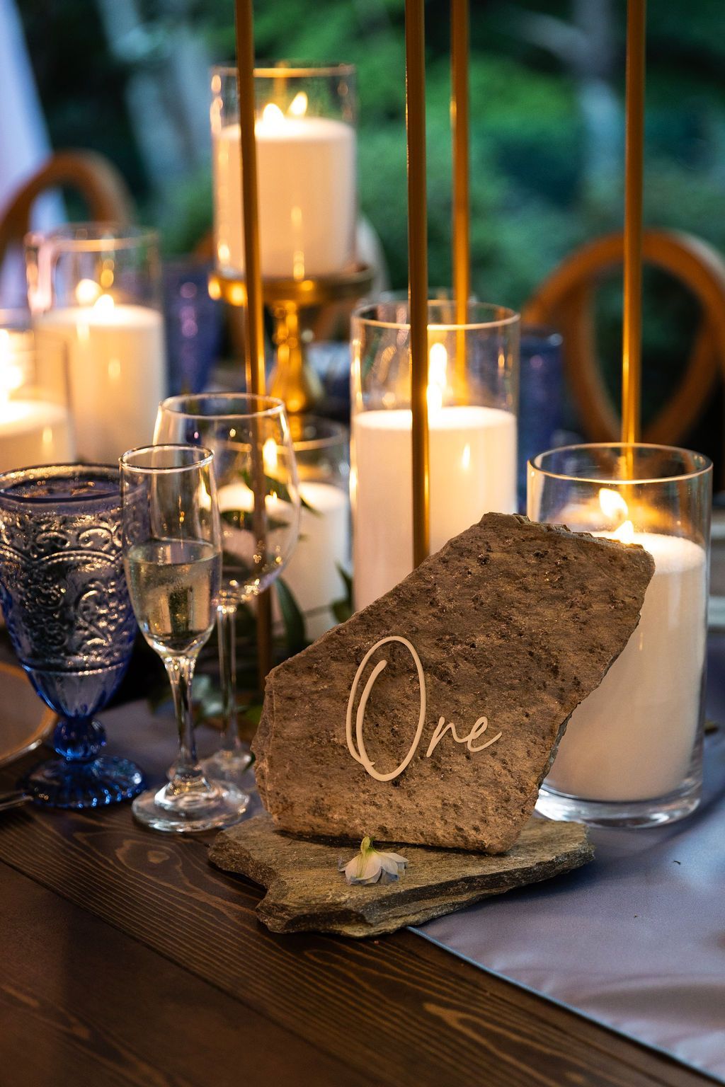 Rustic table centerpiece with candles, glassware, and a “One” sign