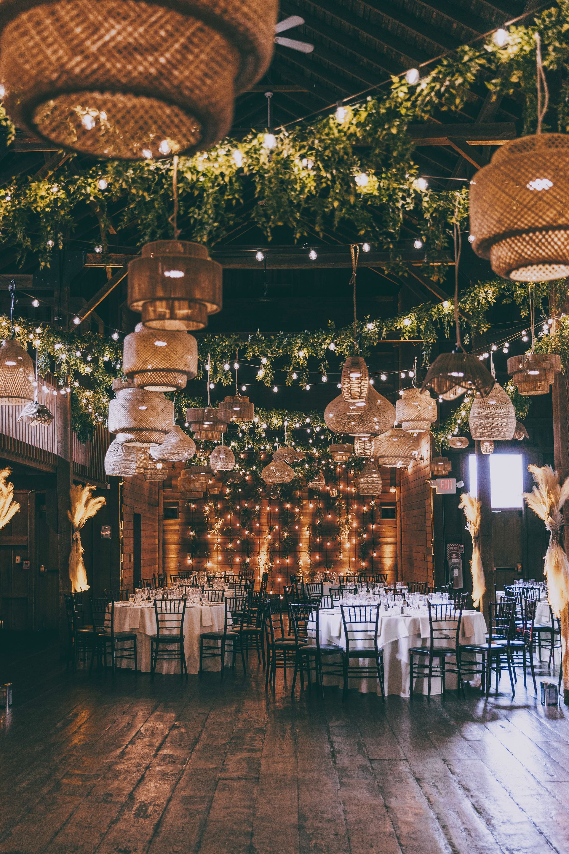 Festive outdoor dining area with hanging lanterns, string lights, and warmly lit tables on a wooden floor