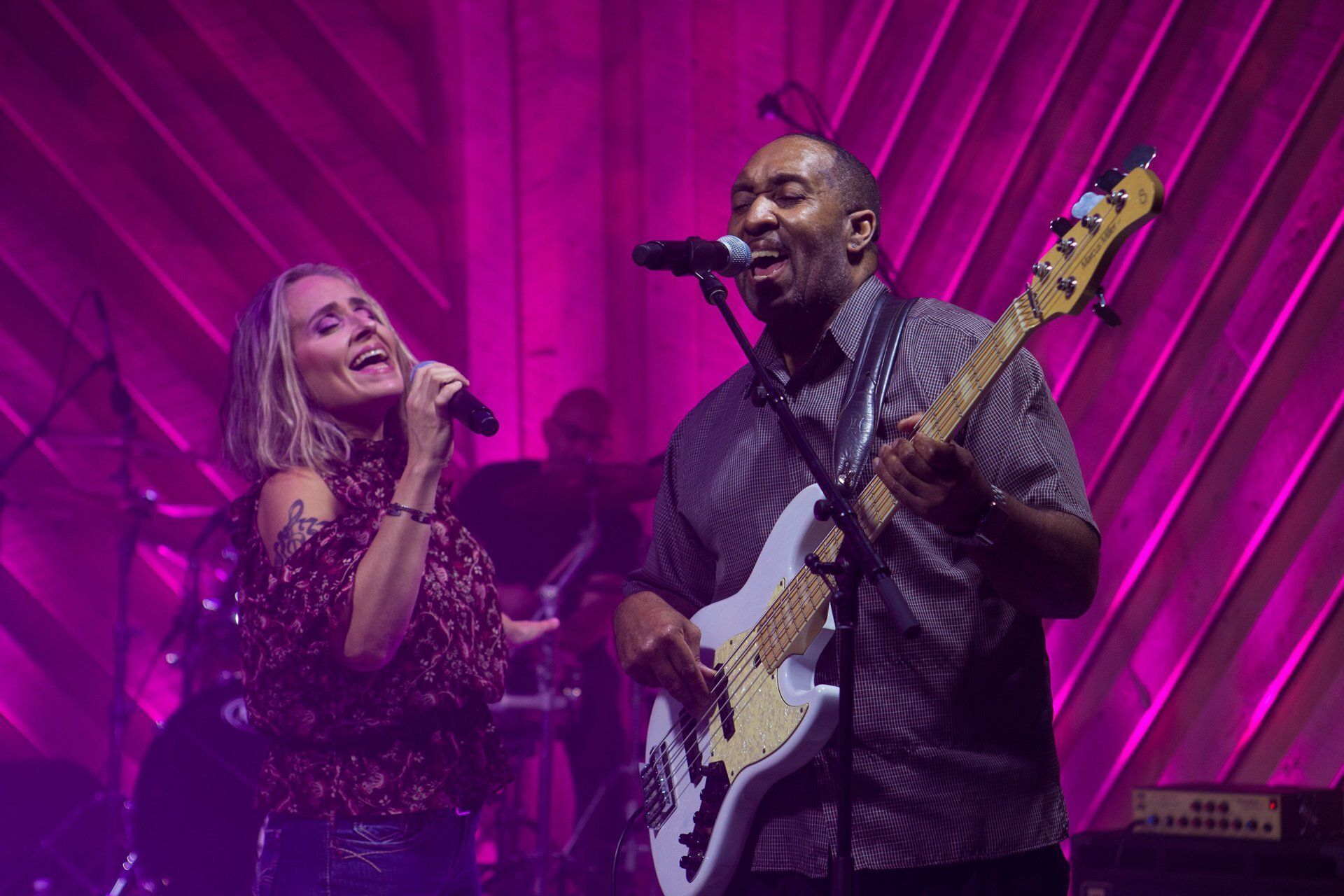 One musician singing into a microphone and another musician singing and playing guitar.