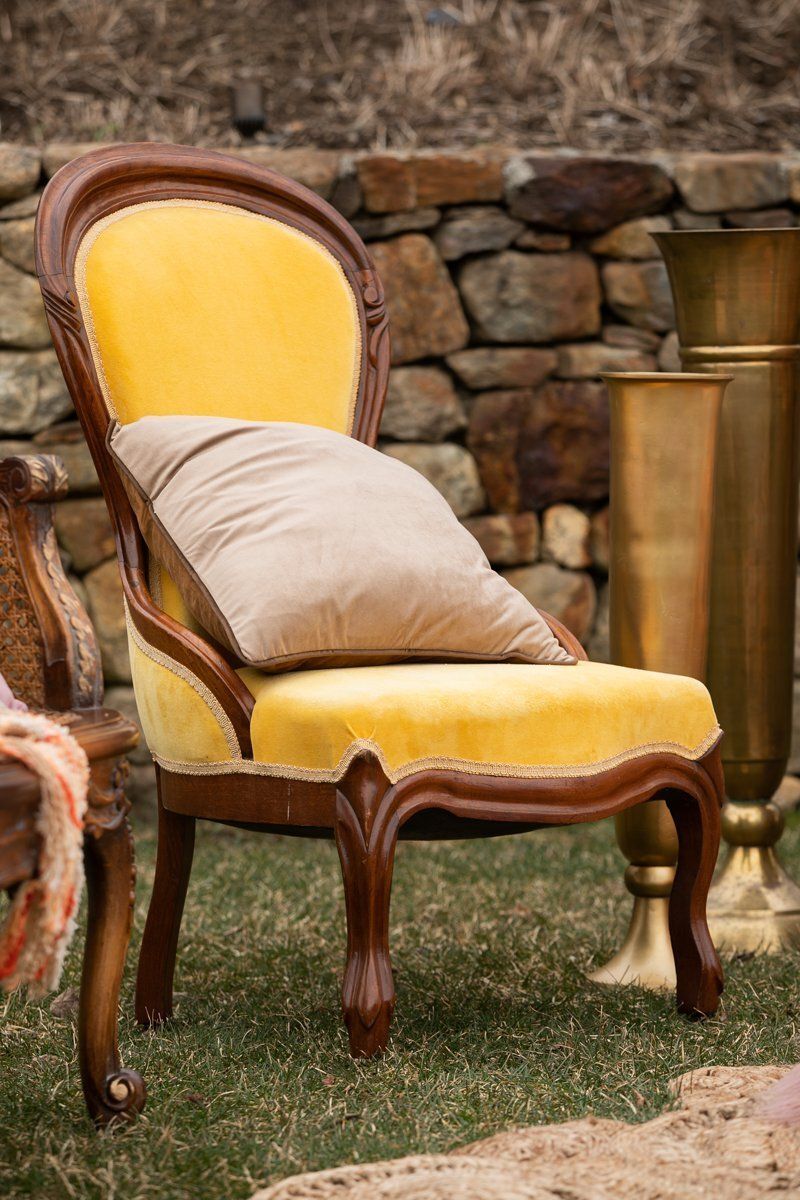 Yellow upholstered chair with a beige pillow in an outdoor rustic setting