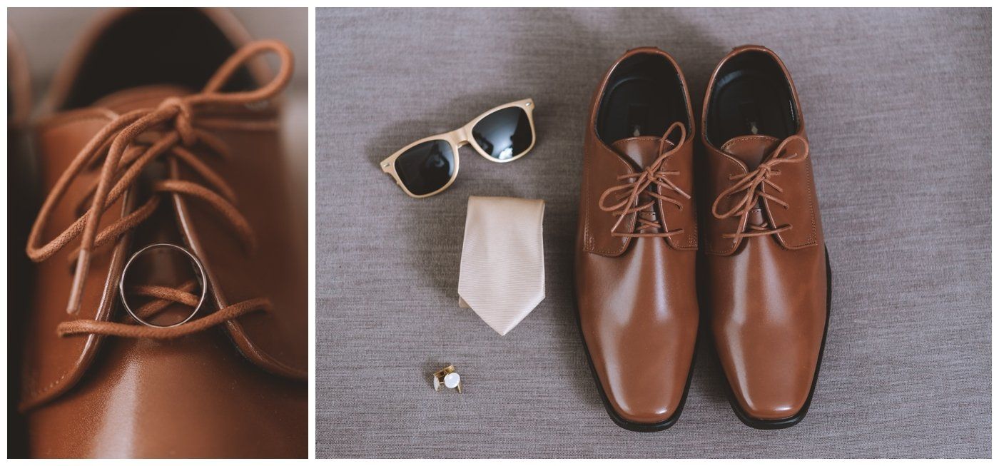 Brown leather dress shoes with sunglasses, a tie, and cufflinks on a gray background