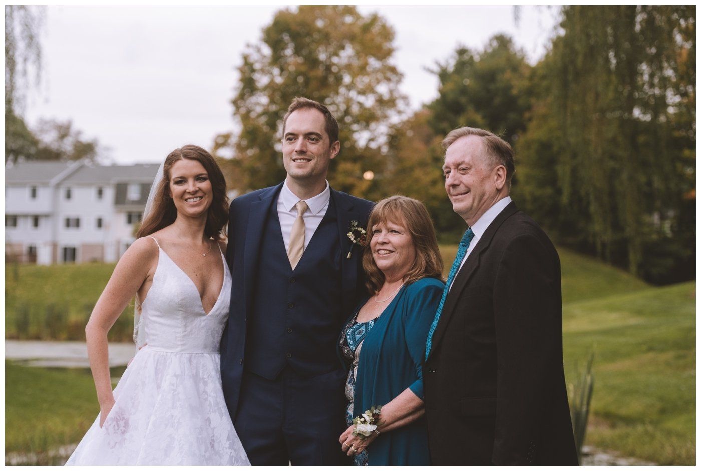 Bride and three guests posing outdoors at a wedding, smiling in formal attire