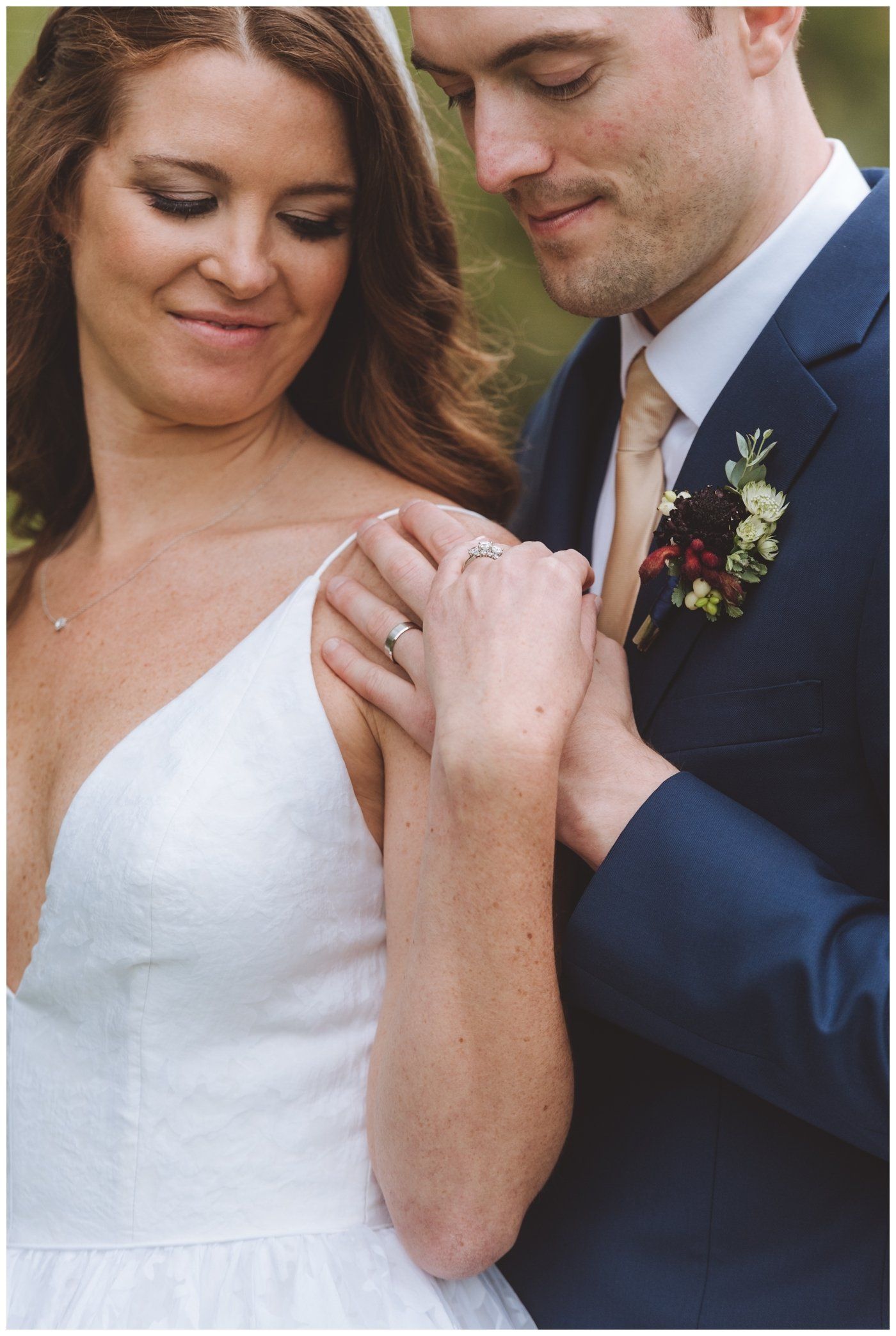 Bride and groom sharing a tender moment, hands touching, with the groom in a navy suit and the bride in a white dress.