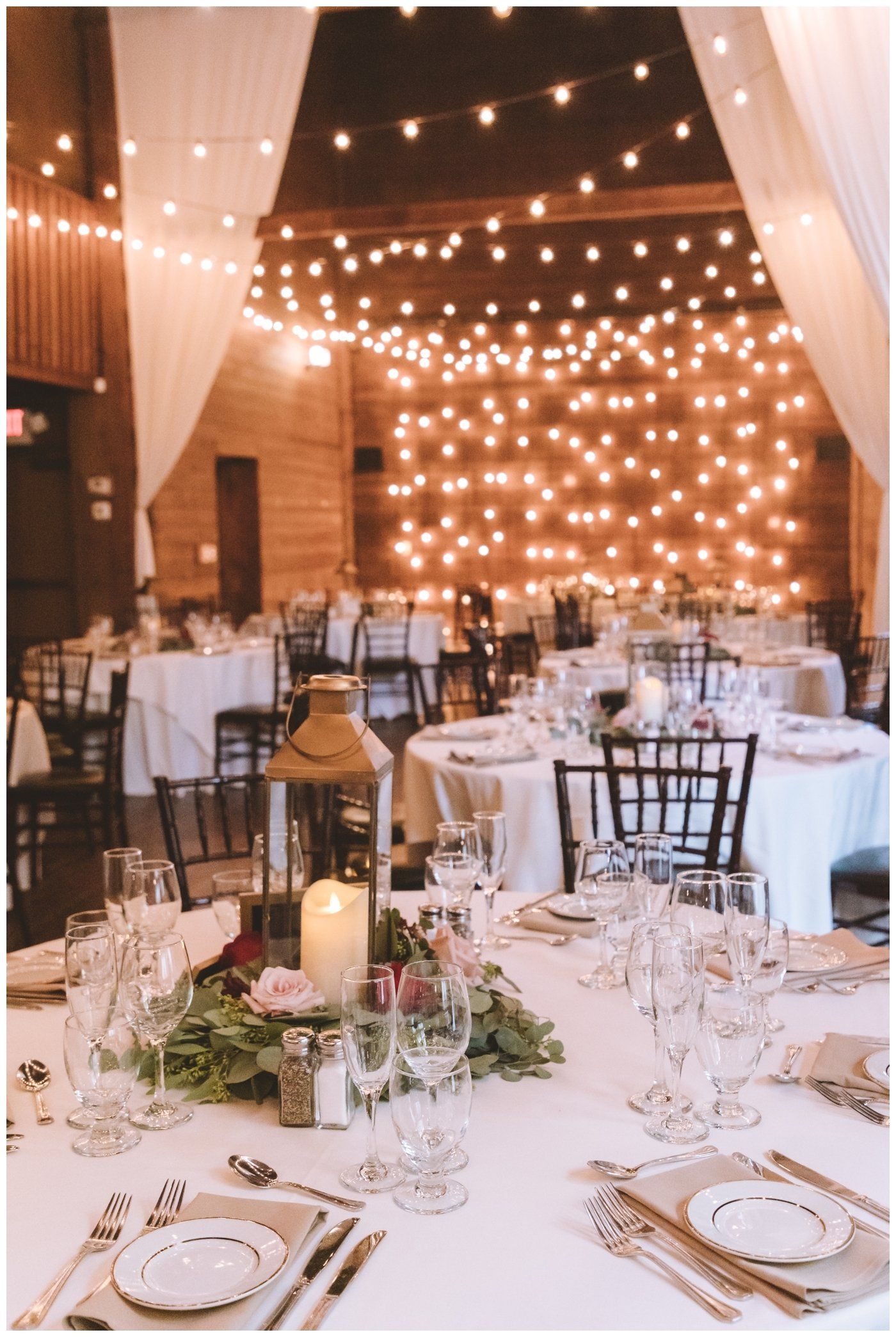 Elegant wedding reception table set under warm string lights in a tented venue
